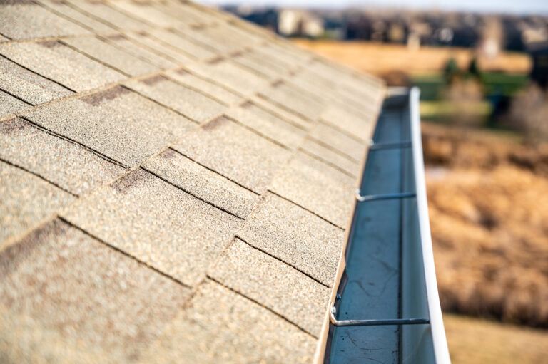 view down a roof gutter with clips and edge of shingles